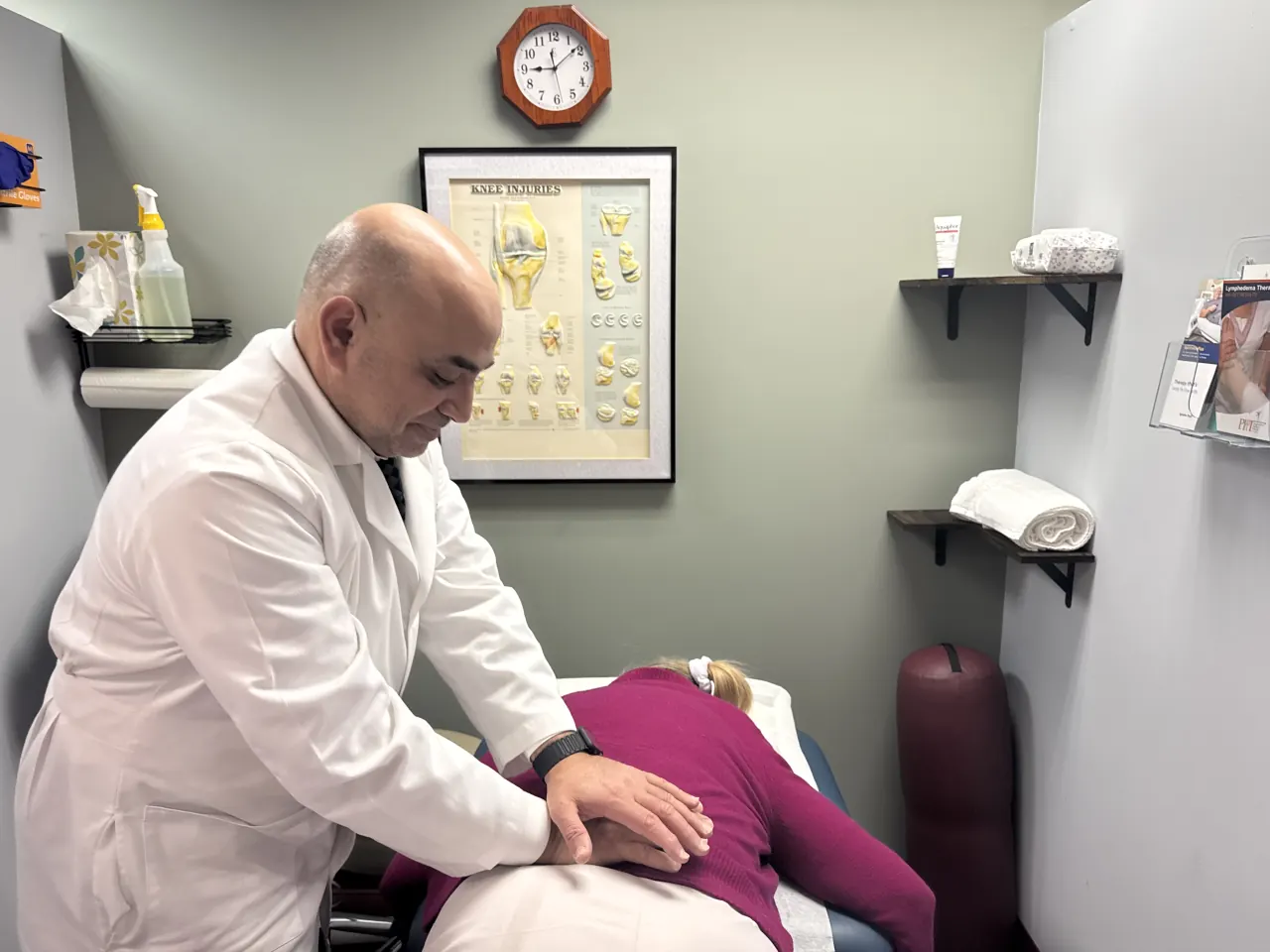 Dr. Omar Hussien performing hands-on manual therapy on a patient at the treatment table